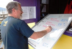 Lions Club volunteer Glenn Brown changes the leader whiteboard at the Bar Harbor weigh-in station Sunday afternoon. (Ed Schoenfeld/CoastAlaska News)
